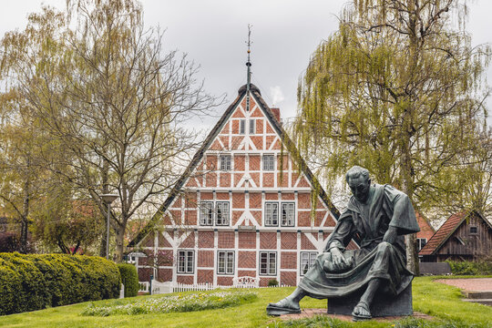 Germany, Altes Land, Half timbered house with statue of priest Heinrich von Carsten Eggers in foreground