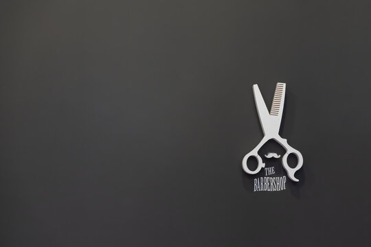Scissor logo on black wall at barber shop