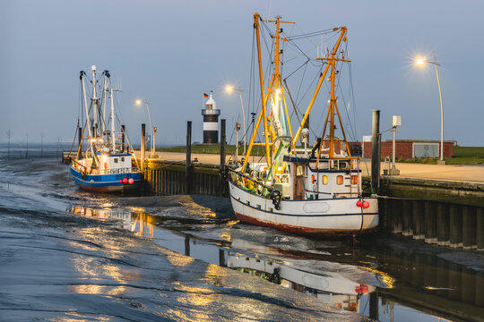 Germany, Lower Saxony, Wurster Nordseekuste, Fishing boats moored in beachside harbor at dusk