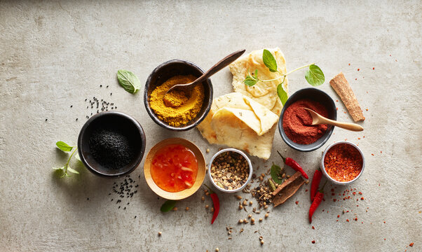 Studio shot of naan bread, chili dipping sauce and bowls with various masala spices