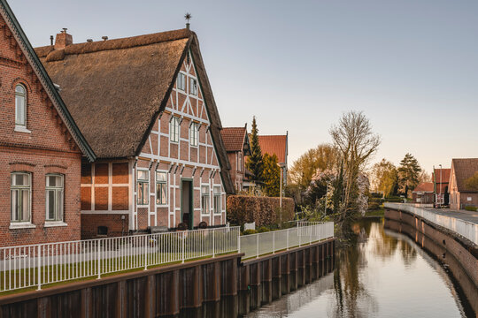 Germany, Altes Land, Jork, Half timbered building over canal at sunset