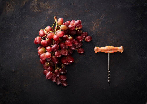 Studio shot of fresh red grapes and corkscrew