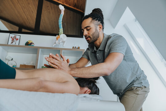 Physiotherapist giving spine massage to female patient in medical practice