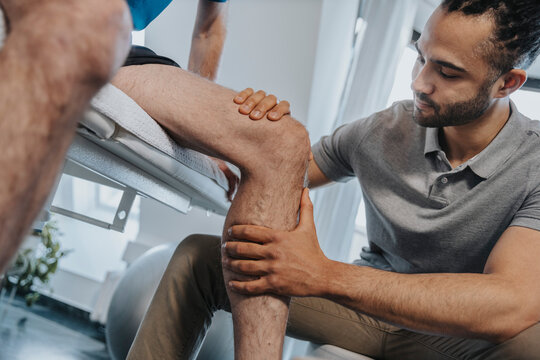 Male Physical therapist examining knee of patient in practice