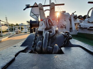 Anchor chain on board the ship. Bright rays of the sun make their way onto the deck of the ship.