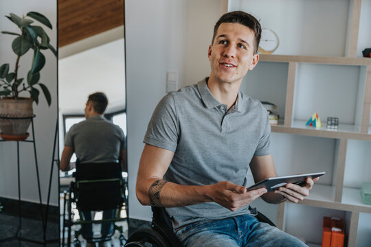 Man with digital tablet looking away while sitting on wheelchair in medical practice