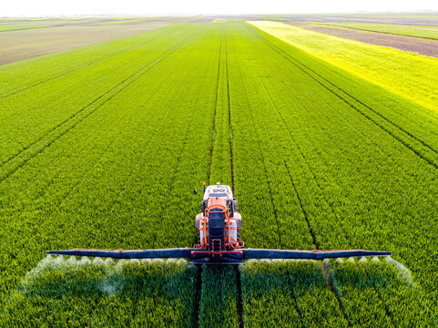 Tractor spraying fertilizer on agricultural field