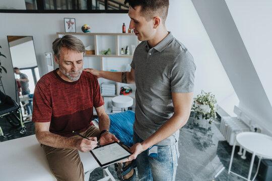 Male patient digitally signing form by physiotherapist in practice