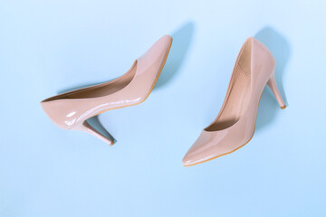 Classic beige women's shoes with medium heels on a blue background. The concept of sales and advertising. flatly. From above.