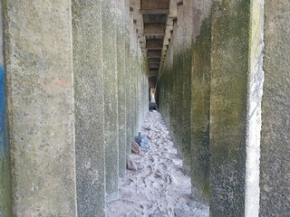 Walkway between concrete pillars.  The path over the stones is located between the concrete pillars on the seashore.