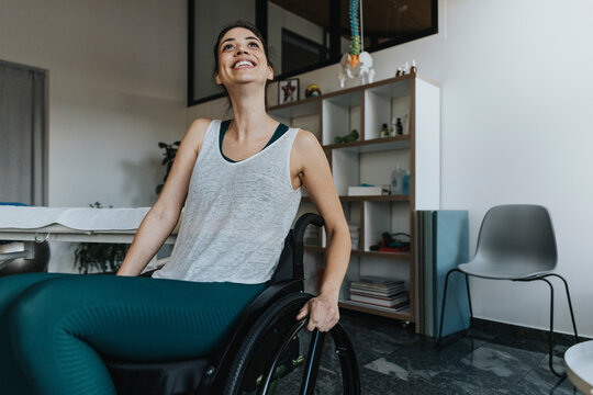 Smiling female patient sitting on wheelchair looking away in medical practice
