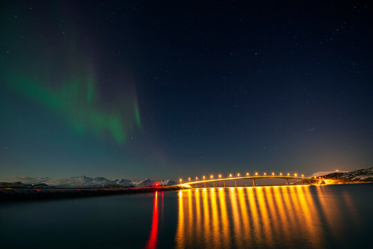 Norway, Tromso, Sommaroy, Aurora Borealis over illuminated bridge