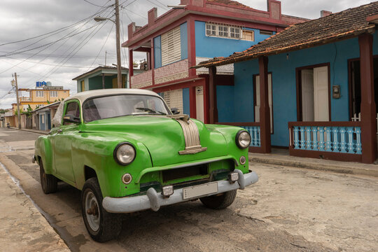 Green old car parked by house in old city