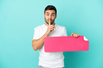 Young handsome caucasian man isolated on blue background holding an empty placard doing silence gesture