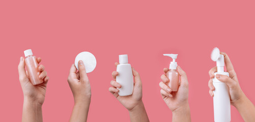 Skincare routine step for healthy skin - Woman hands holding facial cotton pad,  serum, foam,  essential oil, lotion and eye cream packaging on pink background. Beauty and cosmetic concept. Copy space