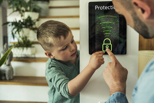 Boy with father touching digital tablet while unlocking in smart home