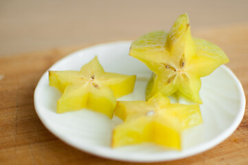 Exotic starfruit or averrhoa carambola on white plate on wooden cut board. Healthy food, fresh...