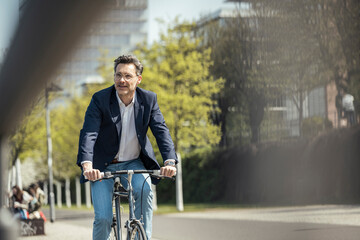 Mature male entrepreneur cycling bicycle on sunny day