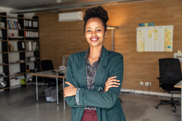 Smiling female professional with arms crossed standing at office