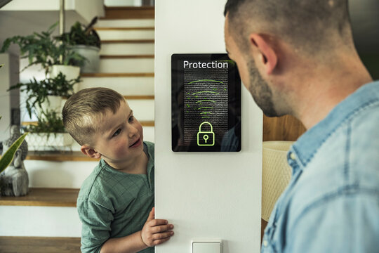Father and son looking at security tablet at smart home