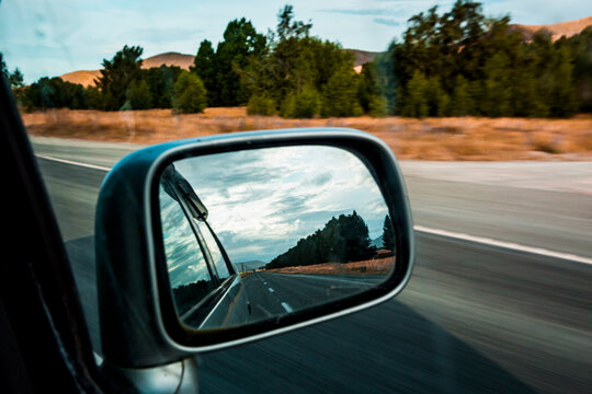 Side-view mirror reflection of car driving along State Highway 8
