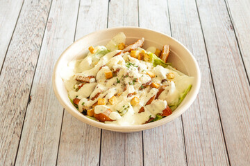 Cesar salad with breaded chicken and mayonnaise served in a home delivery bowl