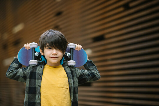 Positive boy with skateboard on street