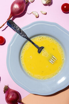 Beaten egg on the plate against ripe red onions