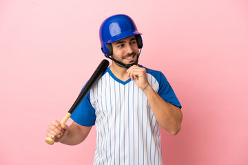 Baseball player with helmet and bat isolated on pink background looking to the side and smiling