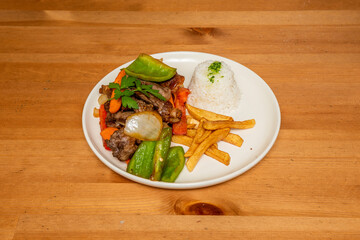 Peruvian lomo saltado with vegetables, homemade chips and bowl of white rice with olive oil and parsley