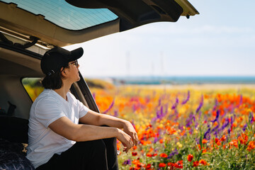 person in car traveling by colorful field