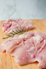 Raw chicken breast with herbs over a wood plate, green background