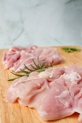 Raw chicken breast with herbs over a wood plate, green background