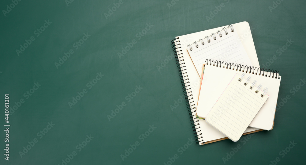 Poster closed notepad with empty white sheets on a green background, top view