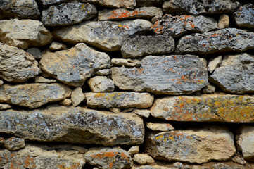 abstract background of old stone wall. the wall is made of old stones of various shapes and sizes. stones are covered with a thin layer of yellowish moss