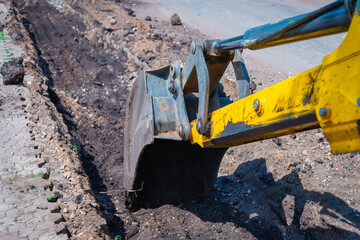 A tractor (excavator) prepares a trench for new curbs.