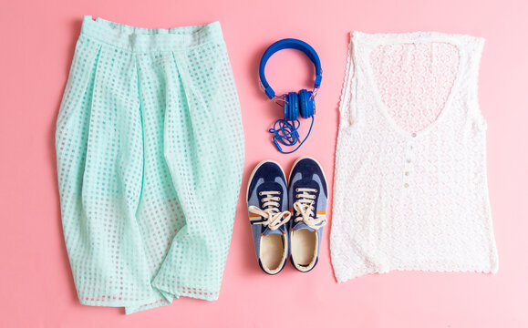 top view of women's clothing, skirt, sweater, headphones and sneakers. Women's summer or spring outfit. flat lay