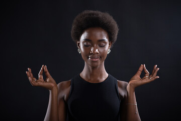 Studio portrait of african american female model showing zen yoga mudra or okay sign gesture. Woman...