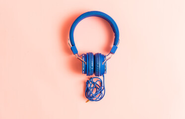 intense blue music headphones on pink background. concept listen to music or podcast. flat lay