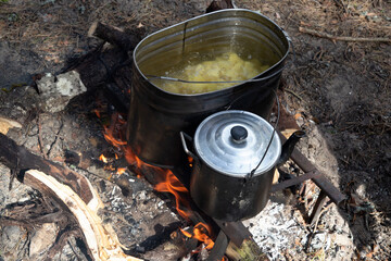 Cooking potatoes in a saucepan over an open fire. Lunch in nature. Tourist food.