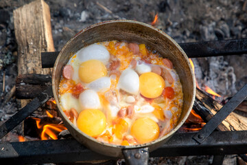 Fototapeta na wymiar Cooking scrambled eggs over an open fire. Breakfast in nature. Tourist food.