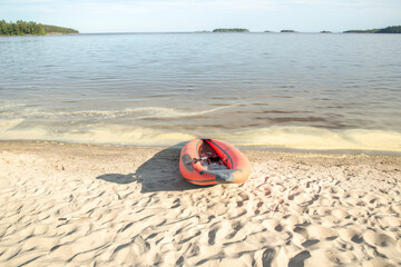 View of the orange kayak on the sandy shore of the lake. Evening landscape.