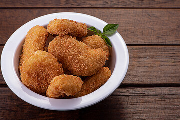portion of nuggets on a white plate on a dark wooden table