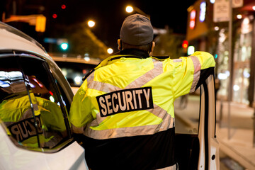 Security guard standing by next to security car at night city