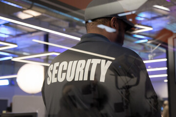 Security guard standing inside a commercial building nearby the window reflecting light