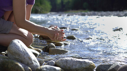 Young European woman hiker washing hands by the river