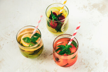 Three different summer healthy drinks, lemonade in glasses with straw on white background. Top view