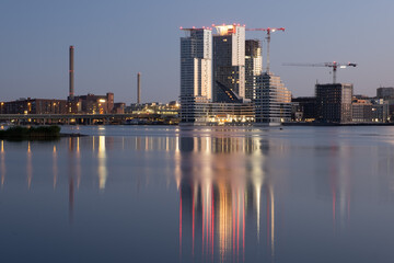 Beautiful modern city skyline on the waterfront during the midsummer evening. Buildings casting reflections on the water.