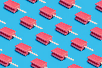 Abstract pattern of kitchen sponges with popsicle ice cream sticks on vibrant bright blue background. Creative hygiene, dish washing and cleaning concept. Pop art aesthetic. Summer texture, flat lay.