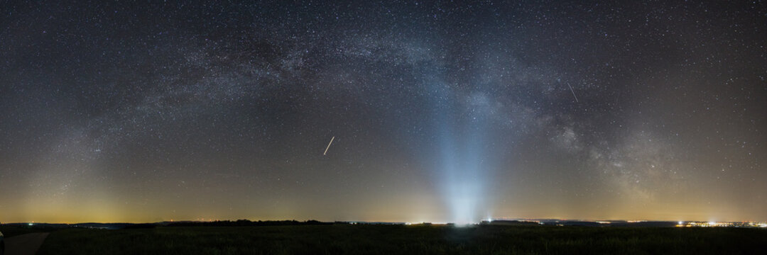 Panorama of Milky Way bow over rural landscape with lights of Spangdahlem Air Base in distance, Germany © Sebastian